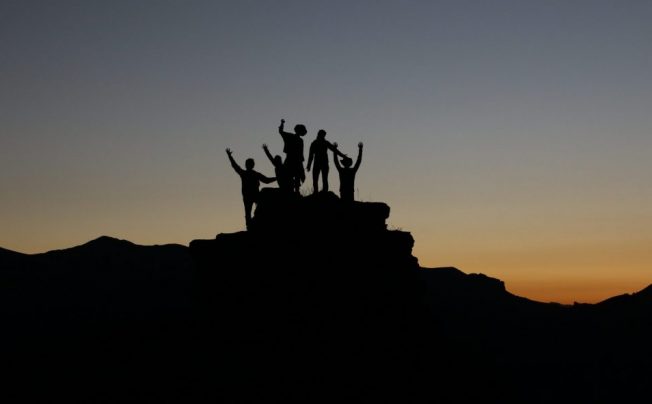 ethical leadership and Effective Leadership as portrayed by people standing on a rock with their fists in the air Participative Leadership