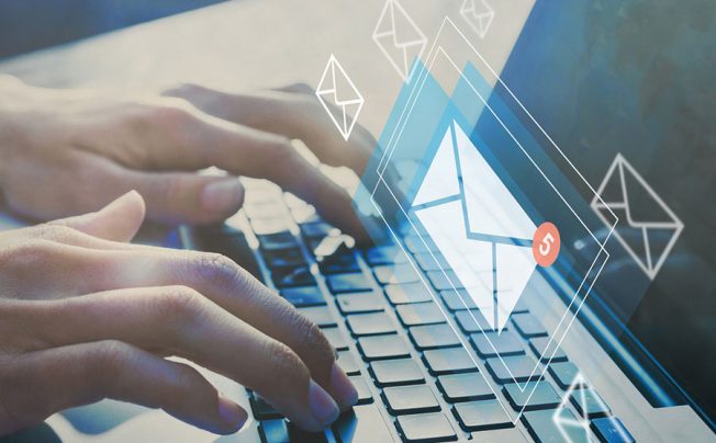 person typing on computer with email icon